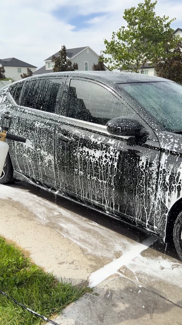 All-Red Detailing washing a vehicle in a customer's driveway